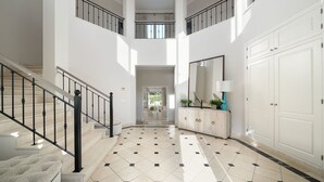 Un interior espacioso con varios niveles, una escalera central, un espejo grande y un armario blanco.