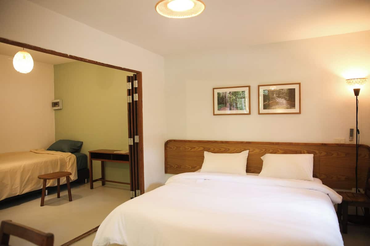 A hotel room with a large bed, two bedside tables, a desk, and two framed pictures on the wall.