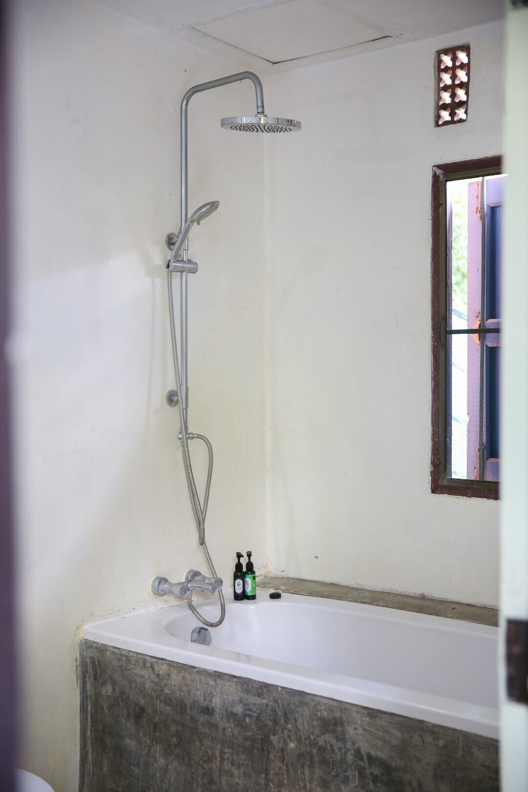 A bathroom with a shower, a bathtub, and a window.
