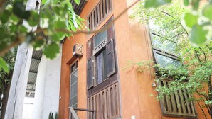 A building with wooden shutters and a window with a metal grate. - Baannoi Nornmuan Homestay Chiang Mai (Chiang Mai)