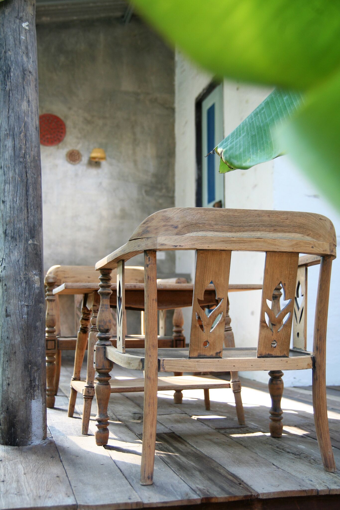 Una silla de madera con detalles tallados, ubicada en una terraza de madera.