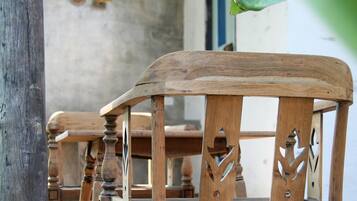 Una silla de madera con detalles tallados, ubicada en una terraza de madera.