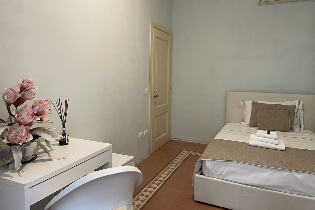 A bedroom with a bed, bedside table, and a desk with a chair.