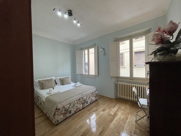A bedroom with a bed, a radiator, a window, and a ceiling light fixture. - Homelink Firenze - De' Medici (Florence)
