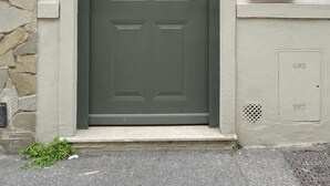 Een donkergroene deur met een cijferslot, een klein raam erboven en een functionele kast aan de rechterkant.