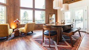 A spacious room with large windows, a wooden dining table, and two chairs. - Summer camp is here at Cle Elum Cabin! Featuring a private hot tub, shuffleboard, games galore, fully stocked kitchen and much more! (Cle Elum)