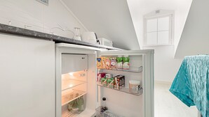 A kitchen with a refrigerator, microwave, and a window.