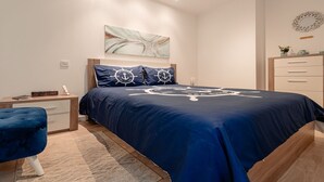 A bedroom with a bed, a nightstand, a dresser, and a blue chair.