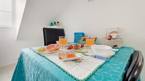 A breakfast setup with a table set for two, including a plate of toast, grapefruit, strawberries, and a glass of orange juice.