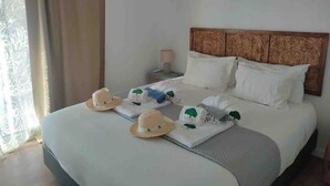 A neatly made bed with white linens, a wooden headboard, and a nightstand with a lamp.
