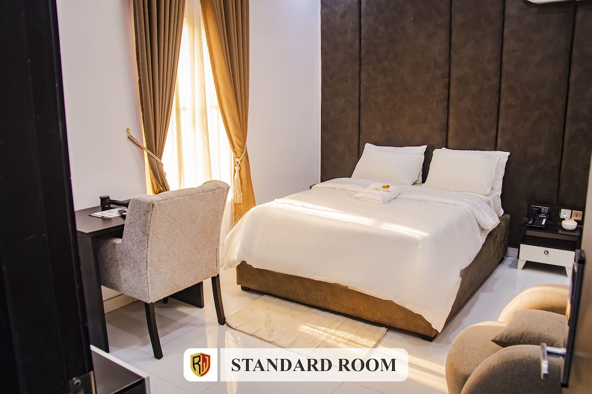A standard room with a bed, bedside table, chair, and a nightstand.