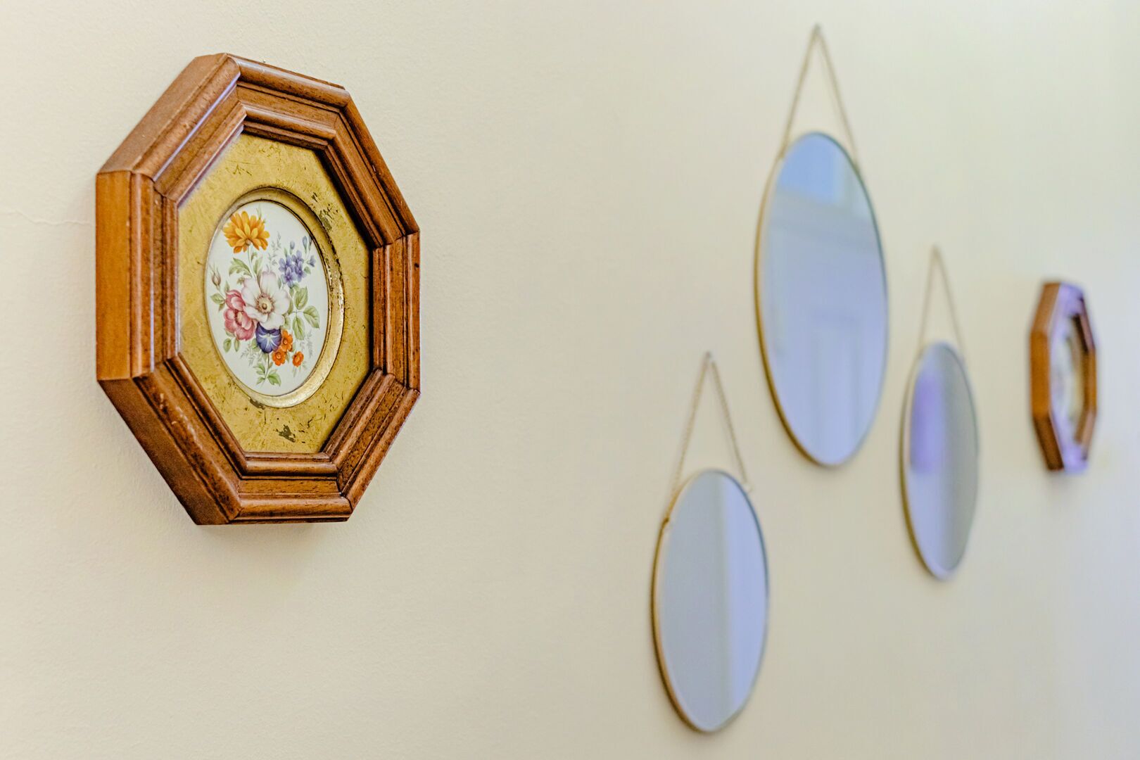 A wall with a hexagonal mirror frame and several oval mirrors.