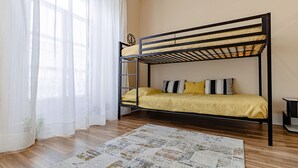 A bunk bed with a yellow bedspread, a wooden floor, and a patterned rug.