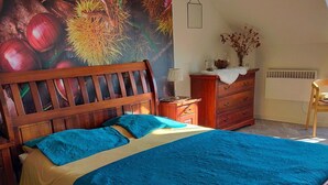 Una camera da letto con un letto in legno, un comodino, una cassettiera e un affresco sulla parete.