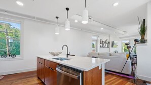 Una cocina moderna con una isla central, lavavajillas de acero inoxidable e iluminación colgante.