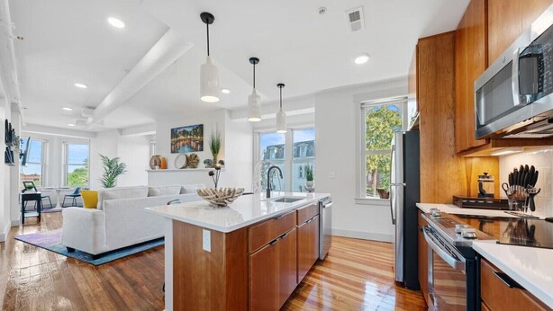 Una cocina moderna con armarios de madera, una isla central y un amplio ventanal que proporciona luz natural.