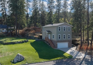 A two-story house with a garage, surrounded by a well-maintained lawn and a stone wall.