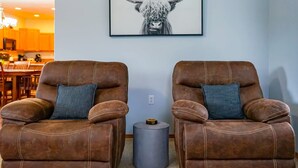 A living room with two brown leather recliners, a gray side table, and a framed black and white artwork of a bull's head on the wall. - Rocky Ridge Retreat | Cozy Post Falls Home (Post Falls)