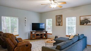 A living room with a ceiling fan, a television, a blue sofa, and two leather recliners. - Rocky Ridge Retreat | Cozy Post Falls Home (Post Falls)
