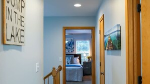 A hallway with a carpeted floor, wooden doors, and a bed in the background. - Rocky Ridge Retreat | Cozy Post Falls Home (Post Falls)
