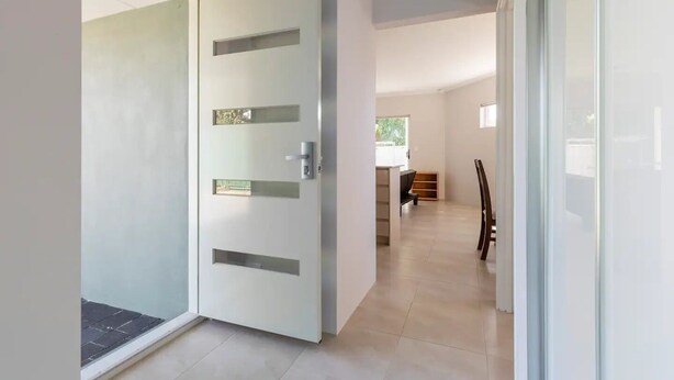 A modern interior with a minimalist door, a dining area with a table and chairs, and a view through a glass door. - Cosy Modern Home close to Fremantle (Coolbellup)