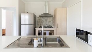 A modern kitchen with a stainless steel refrigerator, a gas stove, and a microwave. - Cosy Modern Home close to Fremantle (Coolbellup)