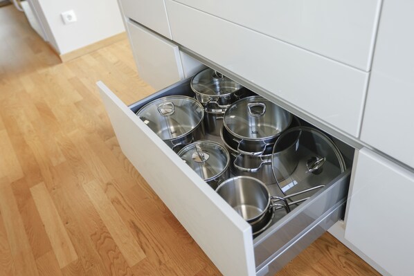 A kitchen drawer with stainless steel pots and pans.