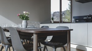A modern dining area with a wooden table, grey upholstered chairs, and a vase with flowers. - 100 m2 Penthouse mit 3 Schlafzimmer, Grosser Überdachter Terrasse und Bergblick (Klaus)