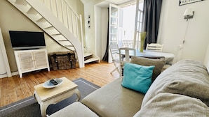 A living room with a staircase, a television, a table, and a sign that reads "LA PLAGE".