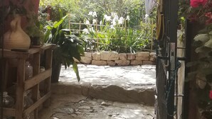 A stone-paved garden pathway leading to a lush, green area with various plants and flowers. - Shillong House by Eco Moyano Posada (Gaucin)