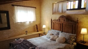 A cozy bedroom with a wooden bed, two bedside lamps, a window with curtains, and a small table with a lamp. - Shillong House by Eco Moyano Posada (Gaucin)