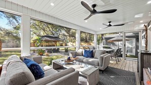Een ruime, overdekte patio met een modern design, voorzien van een grote zithoek, een eethoek en een plafondventilator.