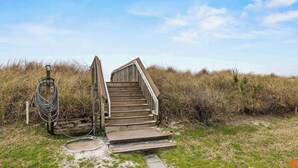 A wooden staircase leading up to a beach access point with a hose and a light post nearby. - Sandy Toes Studio: Your Beachfront Getaway Awaits (Fort Walton Beach)