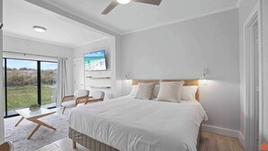 Camera da letto moderna con un letto grande, una TV a parete e vista sull'esterno tramite una porta in vetro.