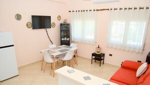 A compact living space with a dining area, a sofa, a TV, and a small cabinet.