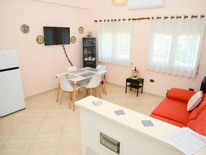 A compact living space with a dining area, a sofa, a TV, and a small cabinet. - 5 minutes from the beach spacious apartment for families and group of friends (Durrës)