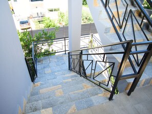 A staircase with stone steps and metal railings, leading to an outdoor area with greenery and a building in the background. - 5 minutes from the beach spacious apartment for families and group of friends (Durrës)