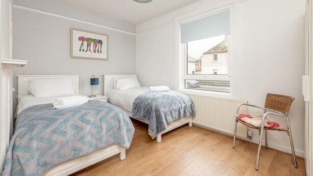 Un dormitorio con dos camas, una ventana con vistas, una silla y una lámpara de techo.