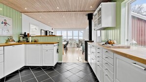 A modern kitchen with white cabinets, a wooden ceiling, and a large window. - 3 bedroom cozy home in Skibby (Skibby)