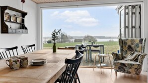 A dining area with a wooden table, chairs, and a view of a lake. - 3 bedroom cozy home in Skibby (Skibby)