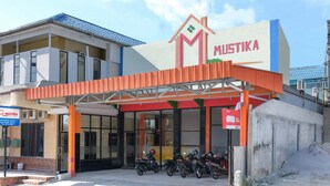 A building with a sign reading "MUSTIKA" and a covered entrance area with parked motorcycles. - OYO Life 1149 Hotel Mustika (Tanjung Pandan)