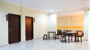 A spacious room with two wooden doors, a dining table with chairs, and a bright ceiling light. - OYO Life 1149 Hotel Mustika (Tanjung Pandan)