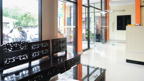 A reception area with a bench, a glass partition, and a view of the outside. - OYO Life 1149 Hotel Mustika (Tanjung Pandan)