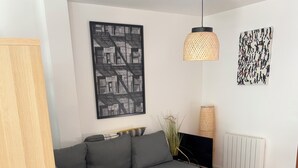 Una sala de estar moderna con un sofá seccional gris, una mesa redonda de centro, un televisor y un radiador.