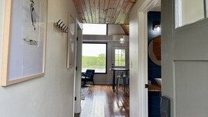 Un corridoio con soffitto in legno, un'area pranzo con due sedie e vista su un lago attraverso una finestra.