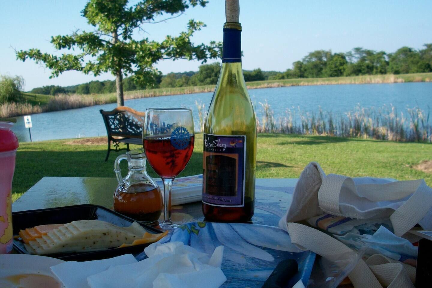 A table with a bottle of wine, a glass of red wine, a pitcher, and some food items.