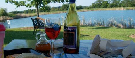 A table with a bottle of wine, a glass of red wine, a pitcher, and some food items.