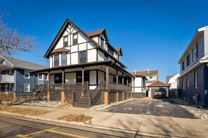 A two-story house with a balcony, a covered porch, and a driveway leading to a garage. - Spacious 7BR Beach House with Arcade and Porch! (Wildwood)