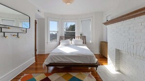 Een slaapkamer met een bed, spiegel, open haard en raam.