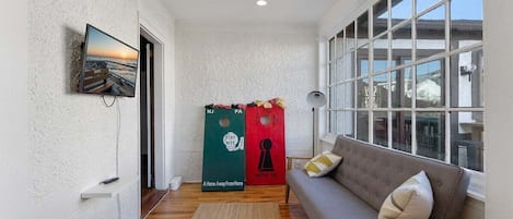 Um quarto aconchegante com sofá, televisão na parede e janela com vista.